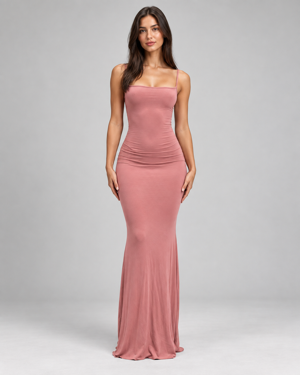 Femme portant une robe Anaïs rose pastel longue et moulante à fines bretelles, vue de face ,douce, féminine et glamour