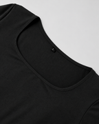 Gros plan sur le col carré et la finition du tissu noir de la robe Laura à manches longues, style épuré et élégant.