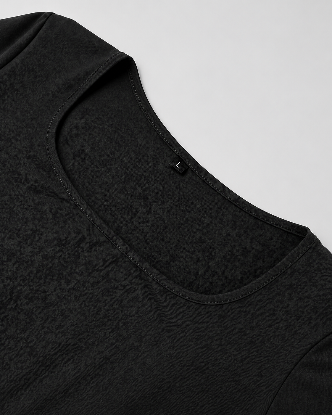 Gros plan sur le col carré et la finition du tissu noir de la robe Laura à manches longues, style épuré et élégant.