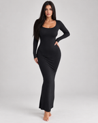 Femme portant une robe Laura noire longue et moulante à manches longues et col carré, vue de face en pied, élégante, féminine et naturelle.