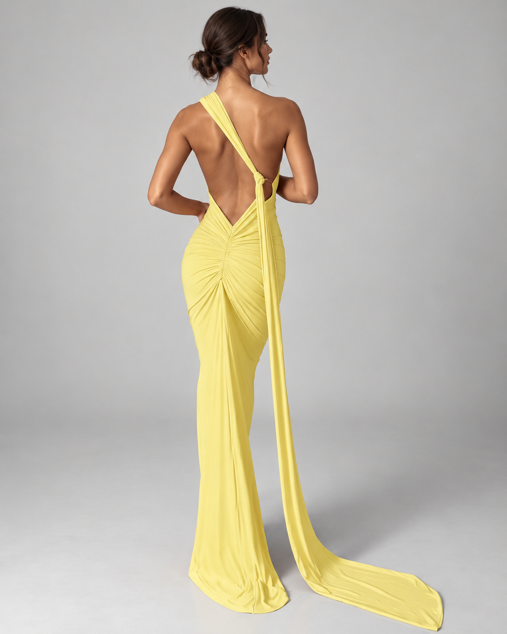 Femme portant la Robe Lina jaune clair vue de dos, avec dos nu profond, détail froncé et longue traîne fluide