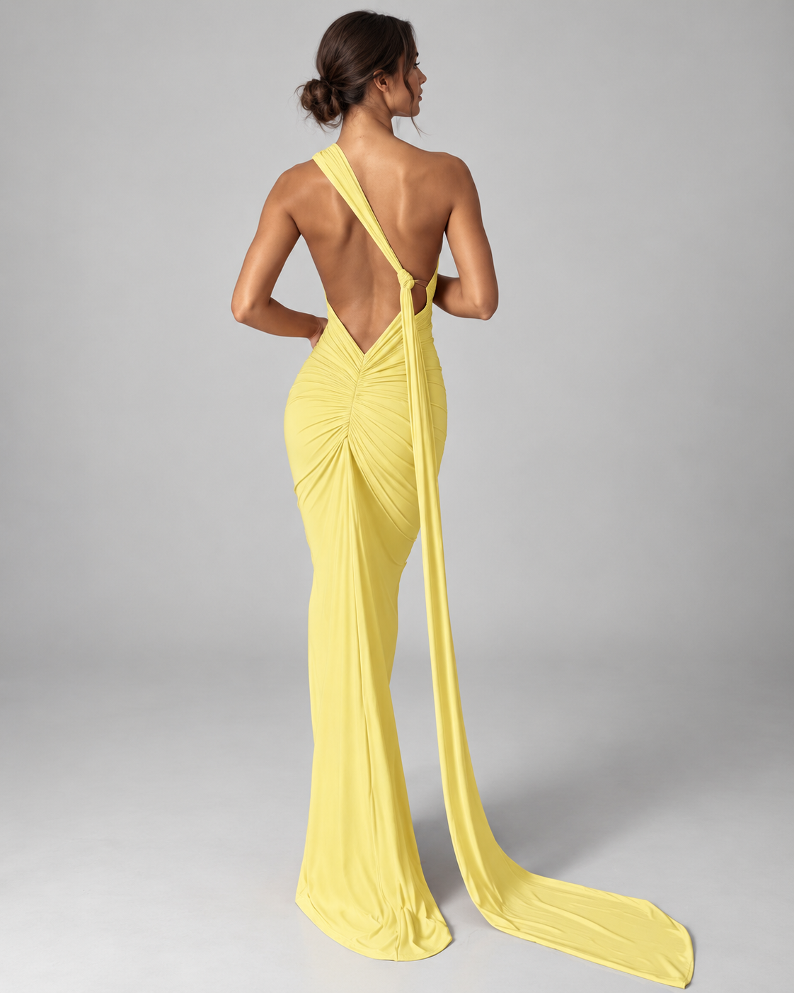Femme portant la Robe Lina jaune clair vue de dos, avec dos nu profond, détail froncé et longue traîne fluide