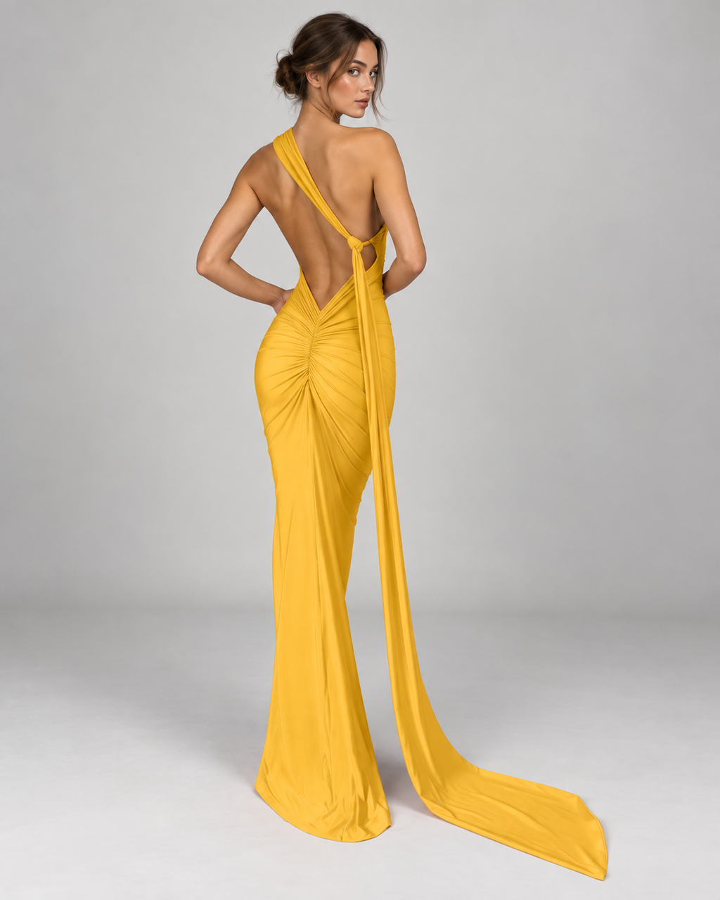 Femme portant la Robe Lina jaune vue de dos, avec dos nu plongeant, fronces au niveau des hanches et longue traîne fluide