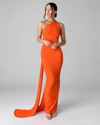 Femme portant la Robe Lina orange, longue et moulante, vue de face avec coupe asymétrique à une épaule et longue étoffe fluide