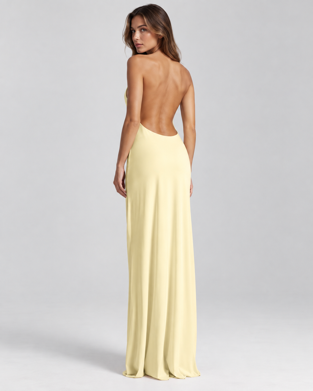 Femme portant une robe Lola jaune longue et fluide à dos nu, vue de dos en pied, élégante, sensuelle et sophistiquée.