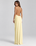 Femme portant une robe Lola jaune longue et fluide à dos nu, vue de dos en pied, élégante, sensuelle et sophistiquée.