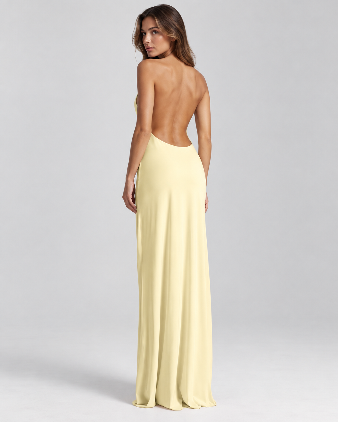 Femme portant une robe Lola jaune longue et fluide à dos nu, vue de dos en pied, élégante, sensuelle et sophistiquée.