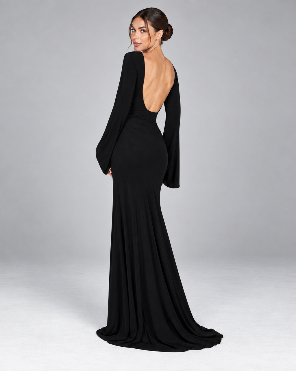 Femme portant la Robe Louise noire vue de dos, avec dos nu plongeant, coupe longue près du corps et manches évasées pour une allure glamour et sensuelle