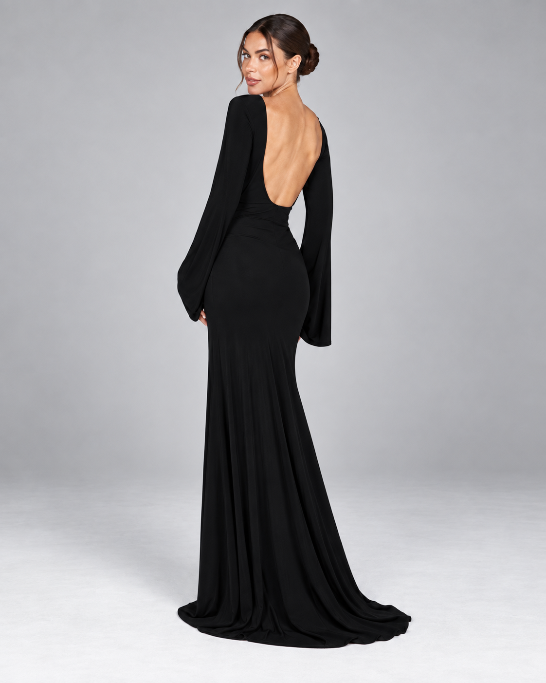 Femme portant la Robe Louise noire vue de dos, avec dos nu plongeant, coupe longue près du corps et manches évasées pour une allure glamour et sensuelle
