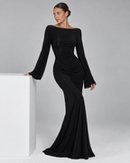 Femme portant la Robe Louise noire, longue et moulante, avec manches longues évasées et encolure dégagée, dans un style élégant, chic et sophistiqué