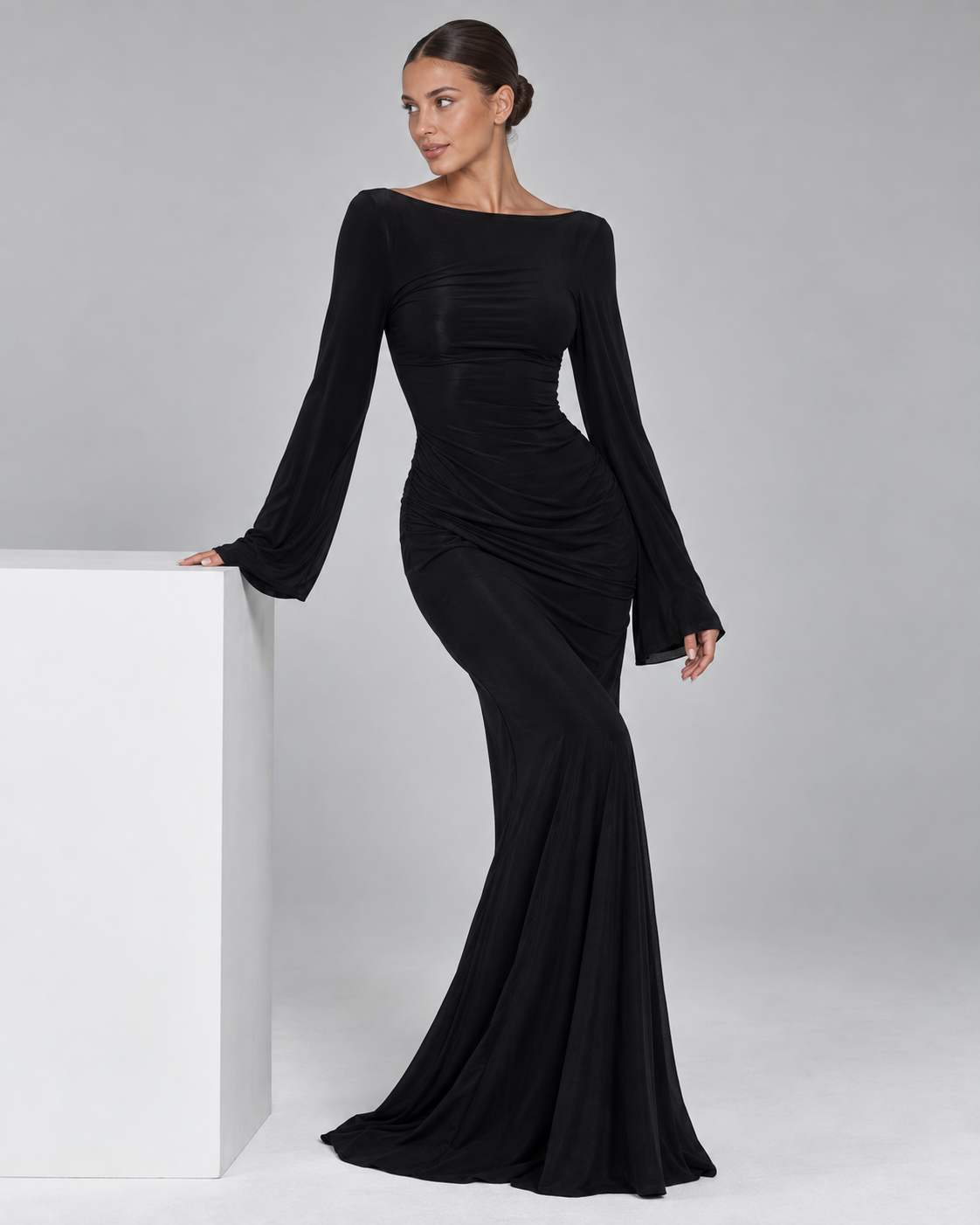 Femme portant la Robe Louise noire, longue et moulante, avec manches longues évasées et encolure dégagée, dans un style élégant, chic et sophistiqué