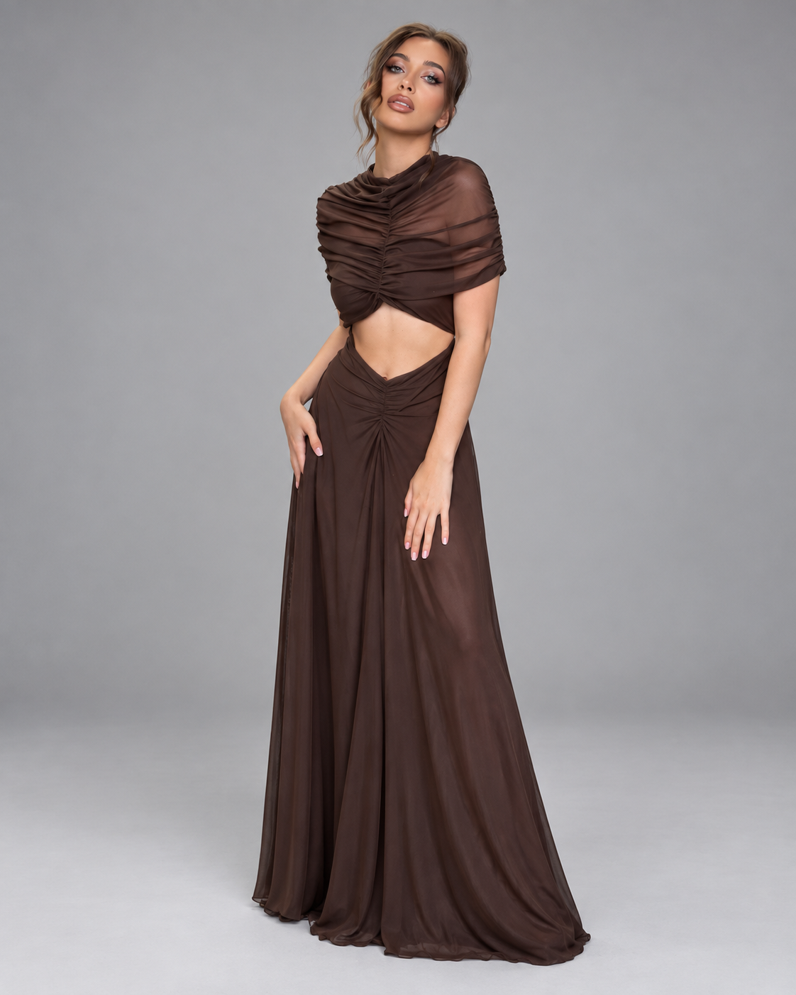 Femme portant une robe Manon marron longue et moulante froncée à découpe taille, vue trois-quarts en pied, naturelle, élégante et sophistiquée