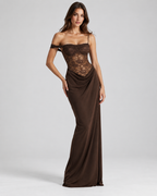 Femme portant la Robe Maya marron , vue de face, longue coupe près du corps avec corsage en dentelle semi-transparente et épaules dénudées, pour une allure sensuelle et sophistiquée