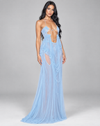 Femme portant la Robe Sofia bleu pastel, longue coupe fluide avec chaînes décoratives et larges découpes, créant une silhouette élégante et sophistiquée